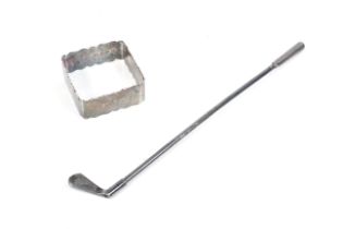 A silver straw in the form of a golf club and a square napkin ring.