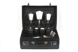An Art Deco silver and enamel mounted travelling dressing table set, in a leather case.