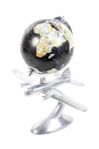 A cast metal model aeroplane mounted on a 20cm terrestrial globe. On a cast metal stand.