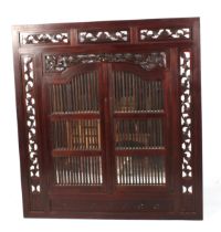 A wood framed wall mirror with window bar doors. With pierced fret work decoration.