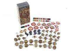 A small tin containing an assortment of military collectables.