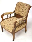 An Edwardian upholstered open armchair. On square tapering supports with casters.