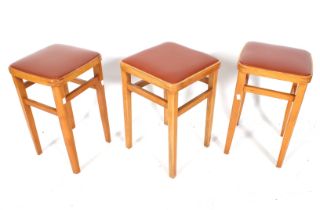 A set of three mid century wooden framed kitchen stools. With vinyl drop in seats.