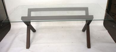 A glass top dining table with 'X' frame support.