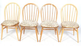 A set of four matched mid-century Ercol dining chairs with arched spindle backs.