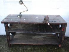 A wooden work bench with a vice and work light.