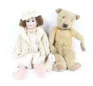 A vintage teddy bear and a bisque head doll. Unboxed.