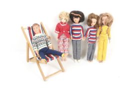 A collection of five various Sindy dolls. In an array of clothing plus a deckchair.