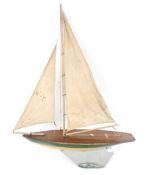 A circa 1930s wooden pond yacht. Finished in green and yellow with a lead keel and cotton sails.