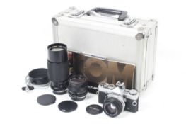 An Olympus OM-1N camera outfit. With three lenses; an Olympus OM 50mm f1.