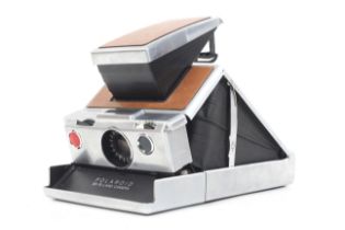 A Polaroid SX-70 Land Camera. Tan and chrome. Together with a case and instructions.
