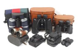 A collection of seven pairs of binoculars.