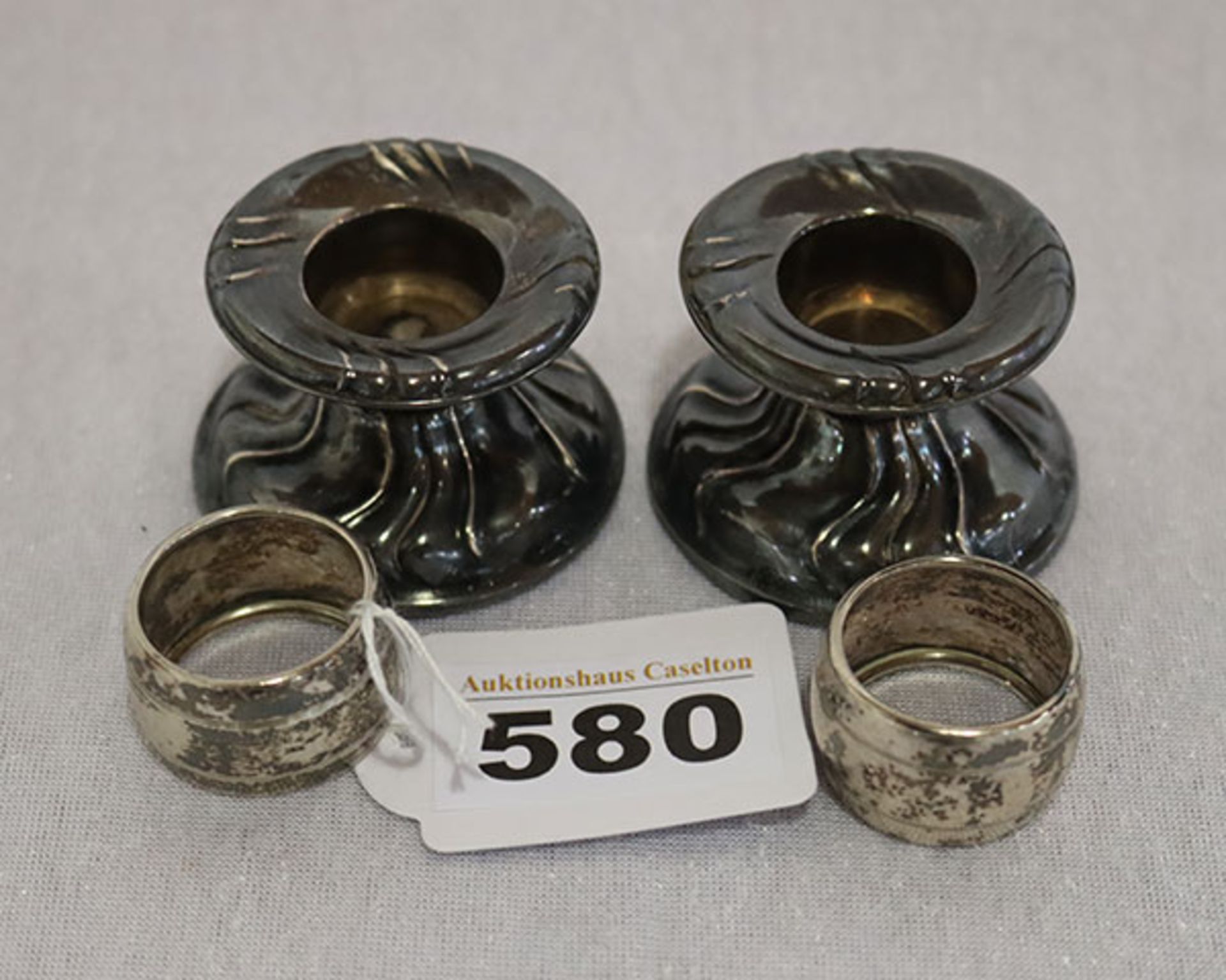 Paar Kerzenleuchter, 835 Silber, gefüllt und verbeult, H 3,5 cm, und Paar Serviettenringe mit