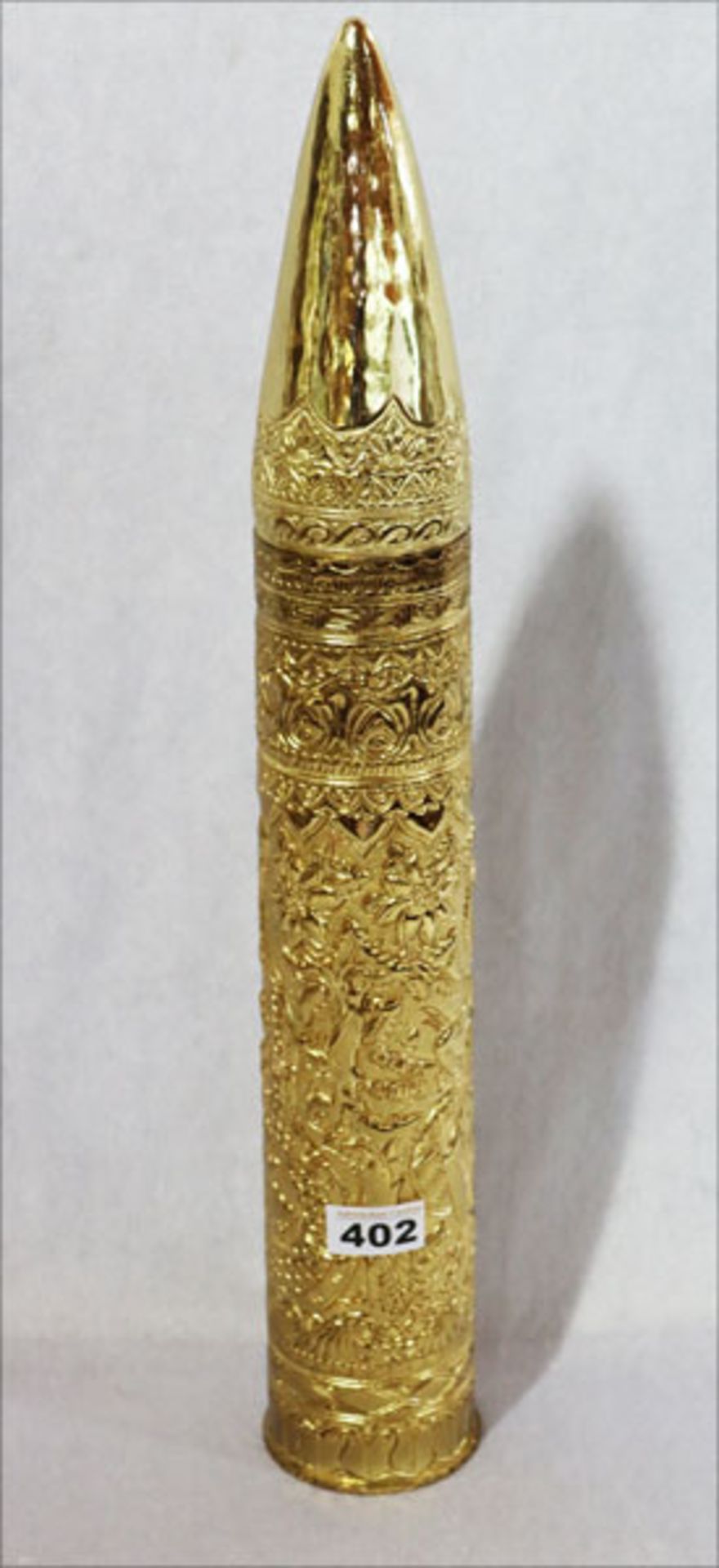 Kartusche eines 75 mm Geschosses mit geprägtem, indonesischem Dekor, vergoldet, H 57 cm