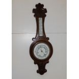 An early 20thC carved oak aneroid banjo barometer with white enamelled dials, 28".