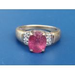 A ruby & diamond set 18ct gold ring, having oval four-claw set ruby above small diamonds to