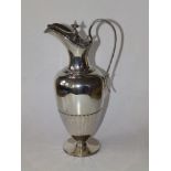 A Victorian silver claret jug of plain design, having leaf cast terminals to the high loop handle,