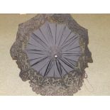 A Victorian black lace-trimmed parasol with floral carved ebonised handle.