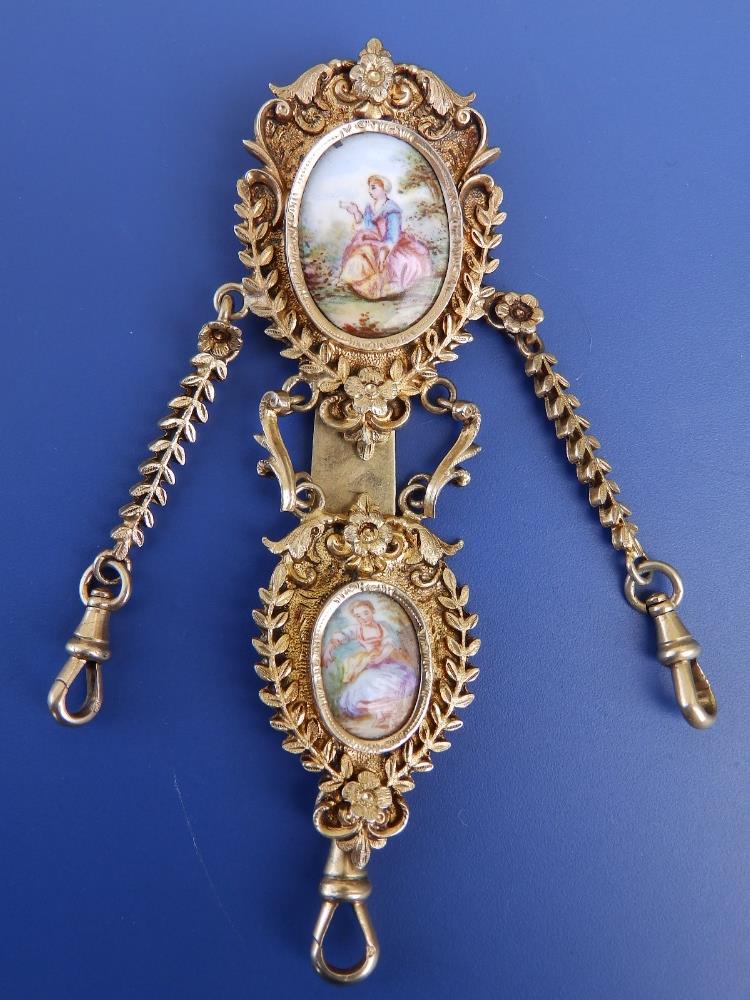 A gilt metal chatelaine in the 18thC style, set with two enamel painted porcelain figural plaques,