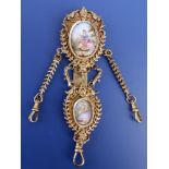 A gilt metal chatelaine in the 18thC style, set with two enamel painted porcelain figural plaques,