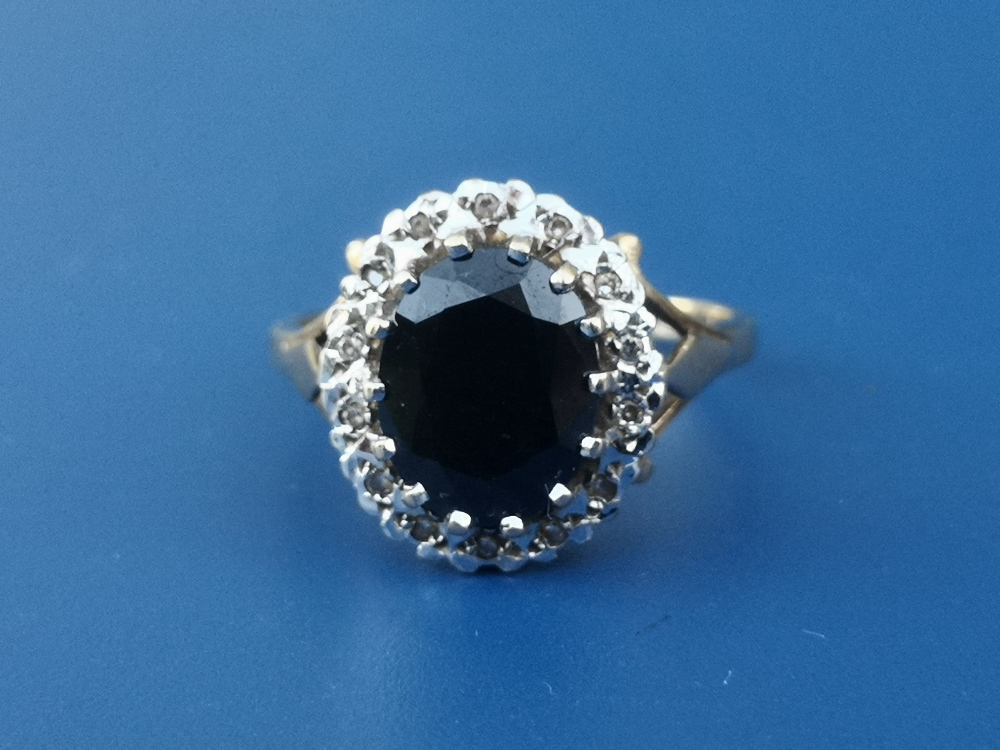 An oval sapphire & diamond set 9ct gold cluster ring.. Finger size O/P.