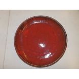 A sang-de-boeuf glazed dish - 'RV', 13.5" diameter.