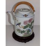 A large 20thC Chinese porcelain cylindrical teapot with cane bound swing handle, 9.5" high excluding