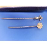 A 9ct stick pin set with a small diamond and one other. (2)