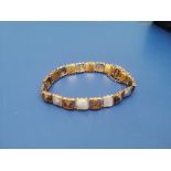 A mother-of-pearl set 15ct gold bracelet by Merle Bennett, the square panel links alternating