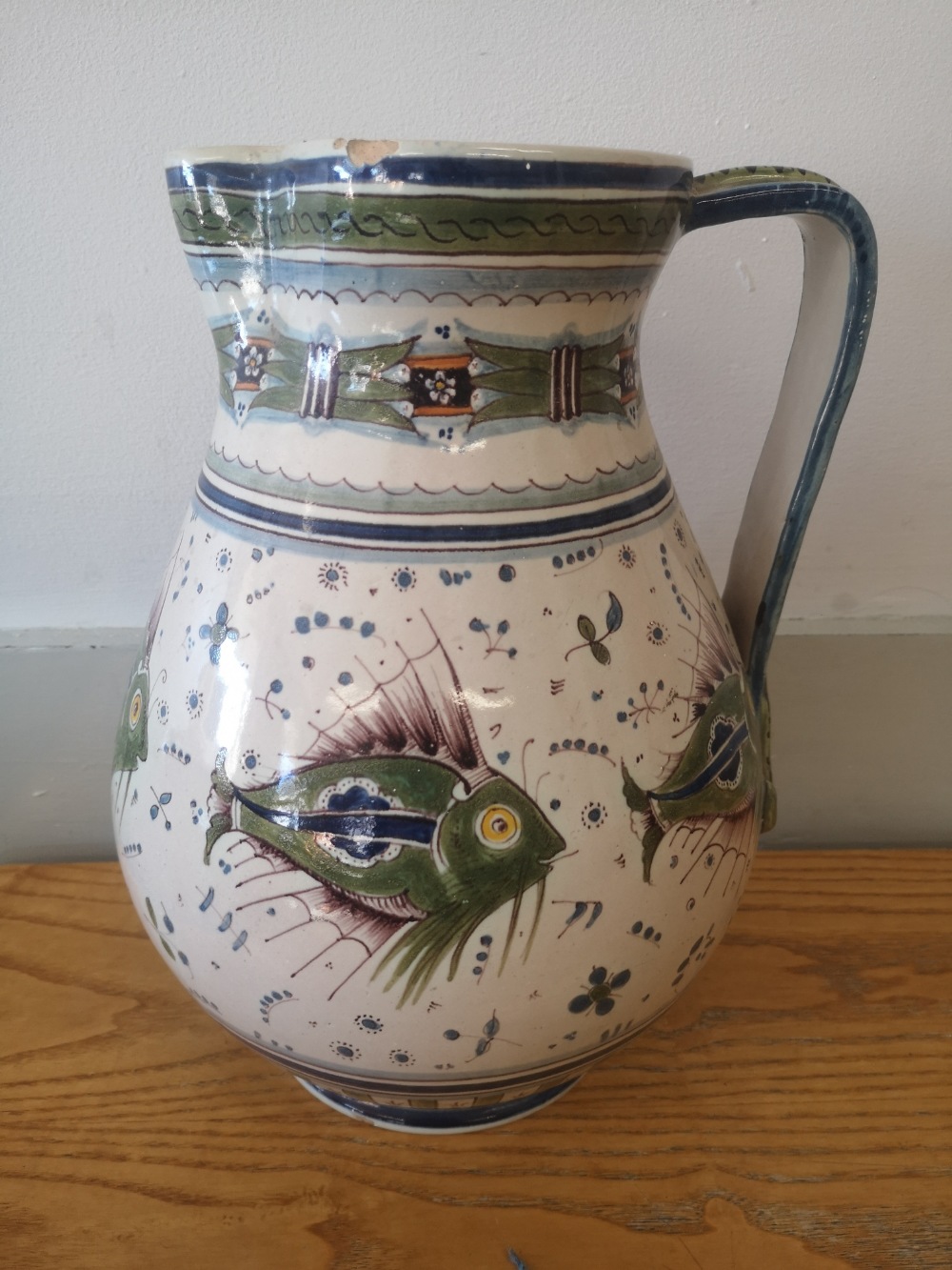 A Cantagalli maiolica jug decorated with fish in green and blue with small flowerheads, blue