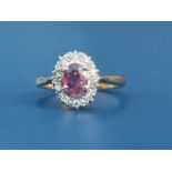 A ruby & diamond set 18ct gold oval cluster ring, Birmingham marks. Finger size M.