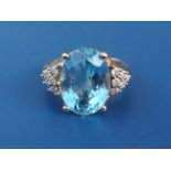 A modern blue topaz & diamond set 9ct gold dress ring, the oval cut topaz weighing approximately 9