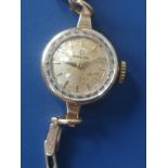 A lady's 9ct gold Omega wrist watch on associated 9ct expanding bracelet - dial discoloured.
