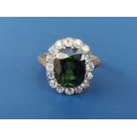 A green tourmaline & diamond set oval cluster ring, the claw set tourmaline weighing approximately