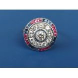 A diamond, ruby & sapphire set target cluster ring in white metal. Finger size O.