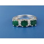 A modern three stone emerald ring with four small diamonds in 18ct white giold. Finger size K/L.