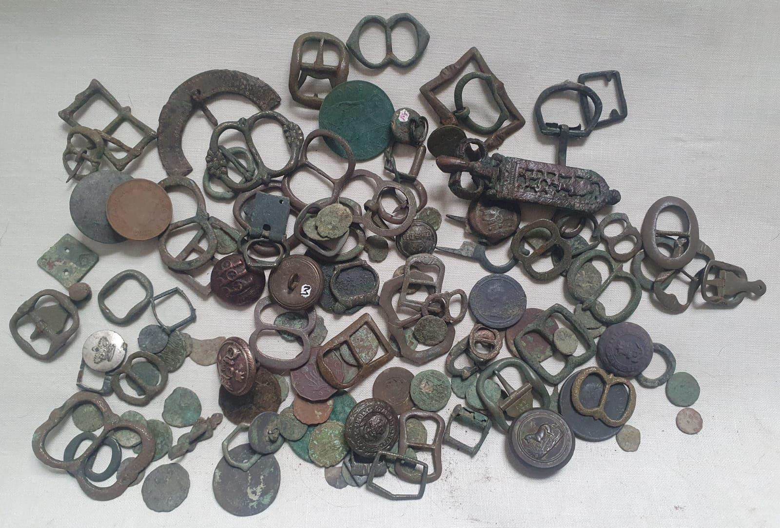 A collection of excavated artefacts including a Saxon and medieval buckles, Roman coins and other