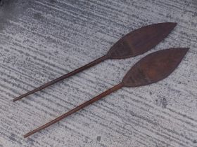 A pair of African carved wood paddles, each having a triangular panel of geometric decoration to one