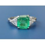 A three stone 2.57 carat emerald & diamond set platinum ring, the rectangular cut four-claw set
