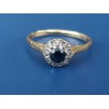 A small sapphire & diamond circular cluster ring on yellow metal shank. Finger size O.