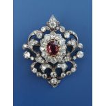 A Victorian ruby & diamond set brooch/pendant, a central oval cut ruby within a cluster of old cut