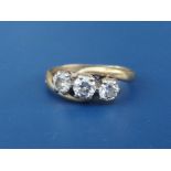 A three stone crossover set diamond ring, the claw set stones of total weight approximately 0.75