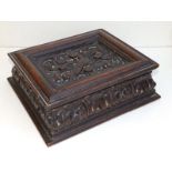 An antique carved oak box, the hinged cover decorated with a dove amongst arabesque leaf scroll,
