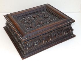 An antique carved oak box, the hinged cover decorated with a dove amongst arabesque leaf scroll,