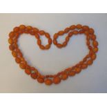 A long certified natural Baltic butterscotch amber bead necklace, comprising 77 graduated oval