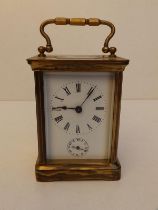 A brass cased alarm carriage clock with white enamel dial, 4" high excluding handle.