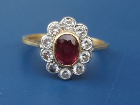 An oval ruby & diamond cluster set 18ct gold ring. Finger size P.