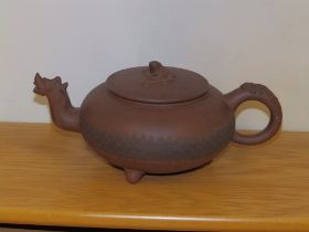 An Oriental red stoneware teapot, having dragon mask spout, incised band of decoration to the low
