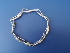 A platinum bracelet of modern design comprising seven elongated twisted links each set with a