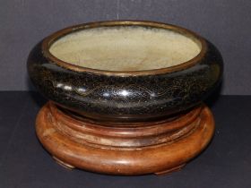 A 19thC Oriental black ground cloisonne dragon bowl on wooden stand, the exterior displaying two